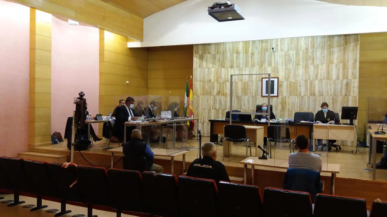 Juicio al supuesto autor del asesinato y enterramiento de su mujer en Guadix, de espaldas, el primero a la izquierda del polic&iacute;a en la imagen
