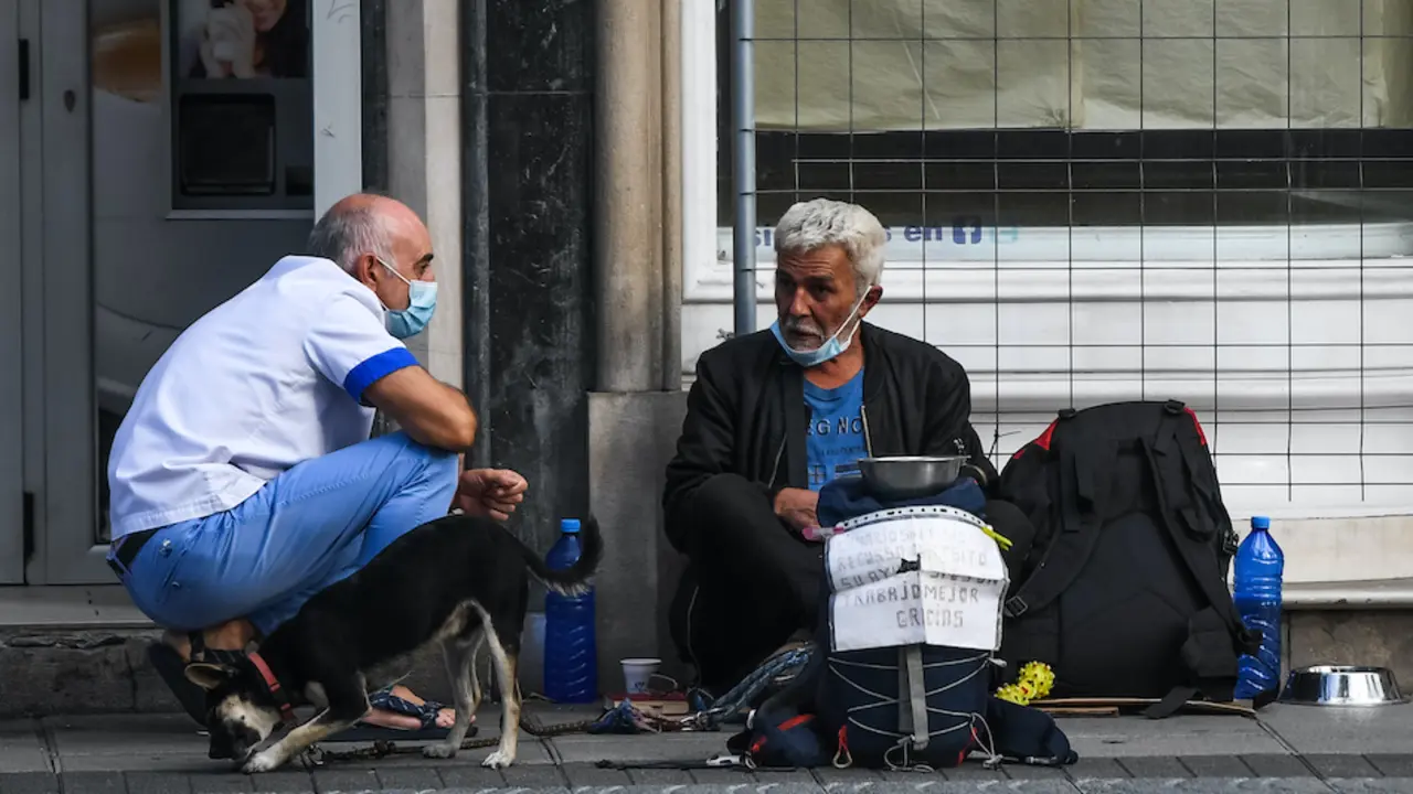 Una persona charla con otra que est&aacute; pidiendo ayuda en la calle la pasada semana, Santander. / Hardy
