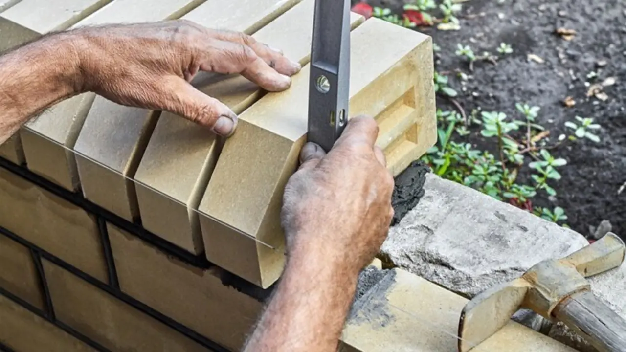 ladrillos-nivelacion-albanil-nueva-cerca-ladrillos-revestimiento-usando-nivel-construccion_98862-1115
