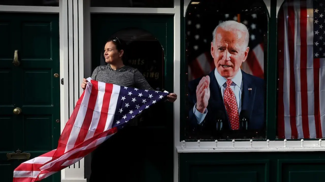 Catherine Hallahan, due&ntilde;a de los barberos de Hallihan, en Ballina sostiene la bandera nacional de los Estados Unidos mientras los residentes comienzan las celebraciones en el hogar ancestral del candidato presidencial estadounidense Joe Biden en anticipaci&oacute;n de los resultados de las elecciones estadounidenses mientras Biden se acerca a la victoria sobre Donald Trump. Foto: Brian Lawless / PA Wire / dpa