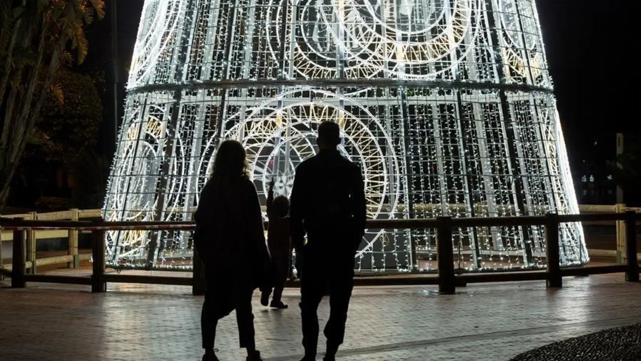 Una pareja y su hijo observan un &aacute;rbol de navidad iluminado en la Plaza de la Marina, en M&aacute;laga. EFE/Daniel P&eacute;rez/Archivo