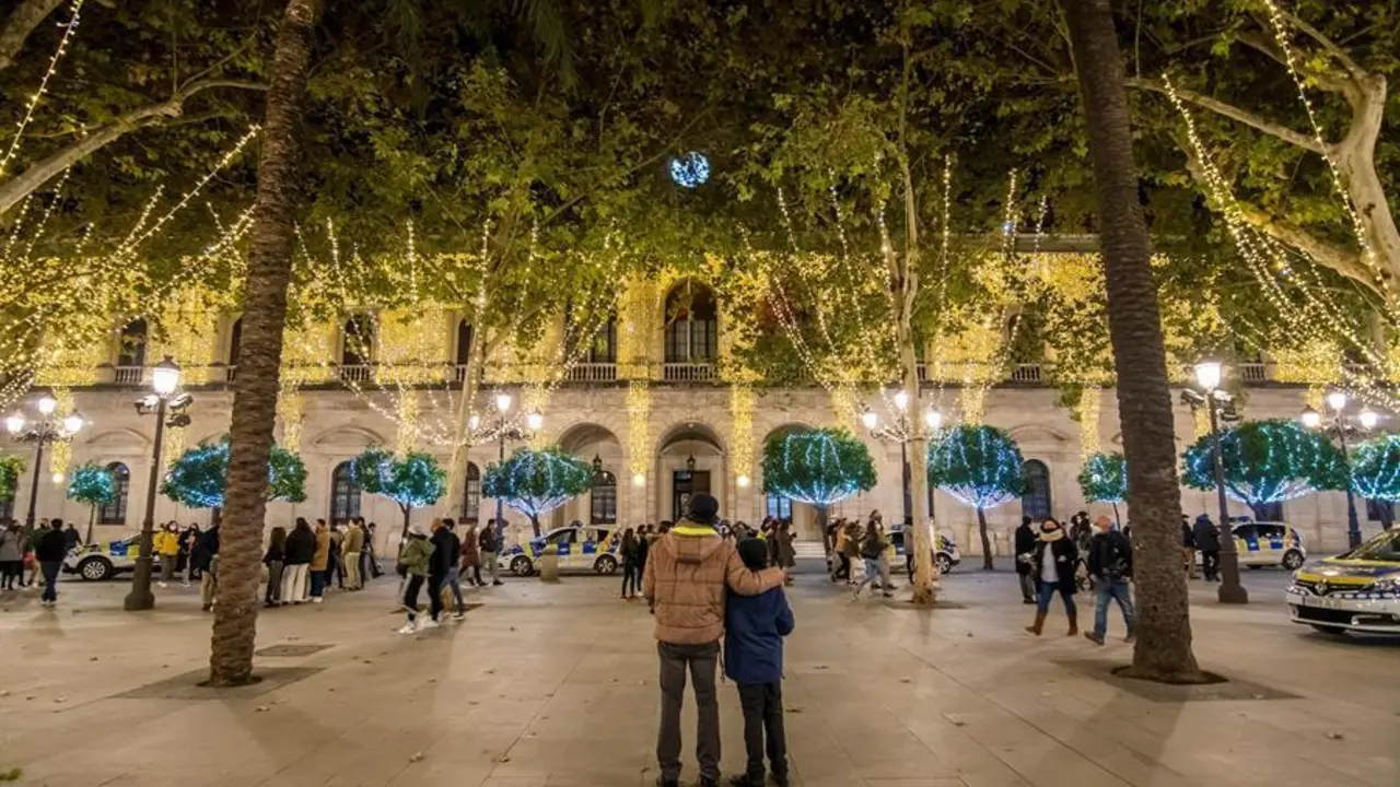 Varias personas disfrutan del encendido navide&ntilde;o en el centro de Sevilla, este s&aacute;bado. La iluminaci&oacute;n navide&ntilde;a de la ciudad de Sevilla ha sido por sorpresa a las 18.30 horas de este s&aacute;bado, como pretend&iacute;a el Ayuntamiento de Sevilla para evitar aglomeraciones en torno al encendido por el coronavirus. EFE/ Ra&uacute;l Caro