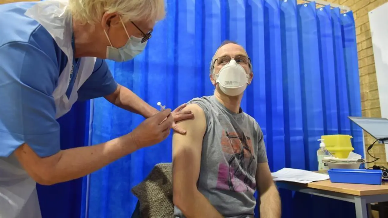 David Farrell, paciente de 51 a&ntilde;os, recibe una de las dos vacunas de Pfizer y BioNtech en un centro de vacunaci&oacute;n hoy, en Cardiff (Reino Unido). El Reino Unido inici&oacute; el mayor programa de inmunizaci&oacute;n de la historia del pa&iacute;s. Los trabajadores a domicilio, el personal del NHS y las personas de 80 a&ntilde;os o m&aacute;s comenzar&aacute;n a recibir la vacuna contra el coronavirus. EFE/Ben Birchal/ POOL