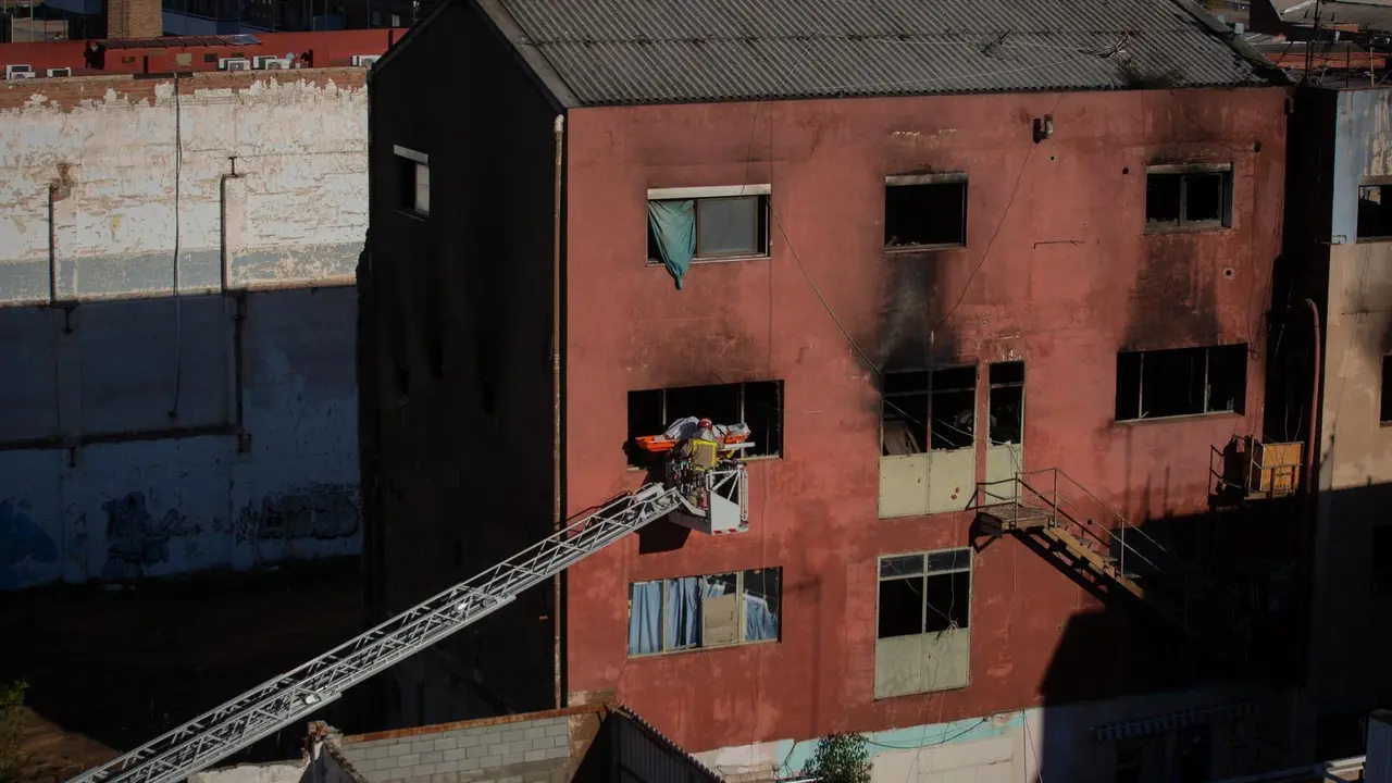 Bomberos retiran el cad&aacute;ver de una de las personas fallecidas en el incendio. / E. PRESS