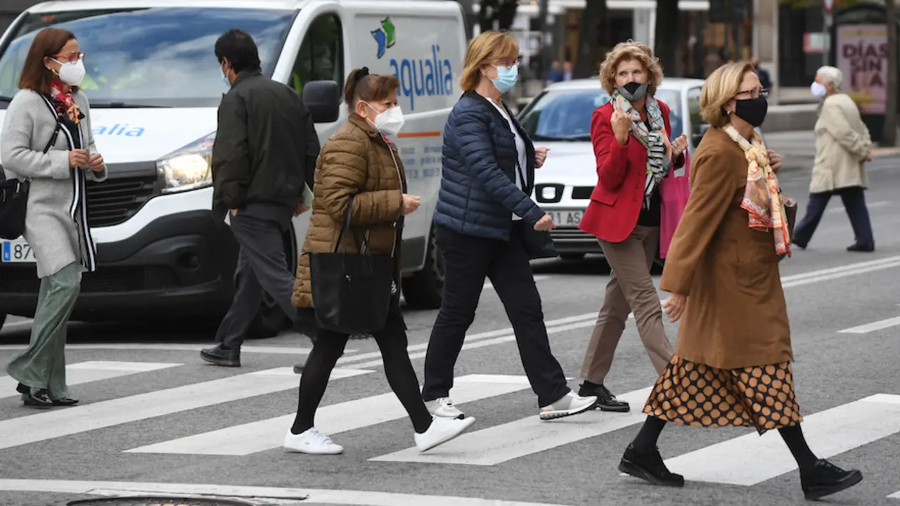 Varias personas cruzan una calle de Santander ataviadas con su mascarilla en el primer lunes tras el levantamiento de la movilidad en Cantabria. / HARDY