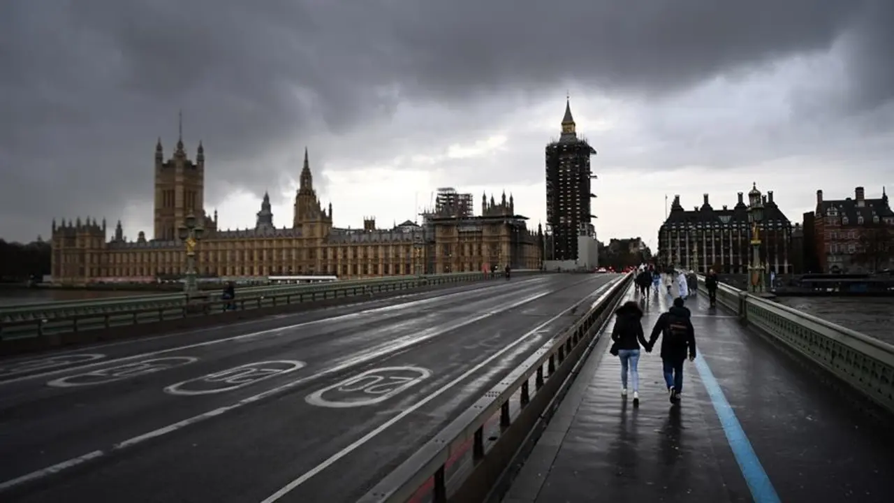 Varias personas cruzan el puente de Westminster, este lunes en Londres (Reino Unido), cuando las autoridades brit&aacute;nicas se est&aacute;n planteando un nuevo cierre de tiendas de ropa, bares y restaurantes en la capital ante el nuevo repunte de positivos por coronavirus. EFE/ Andy Rain