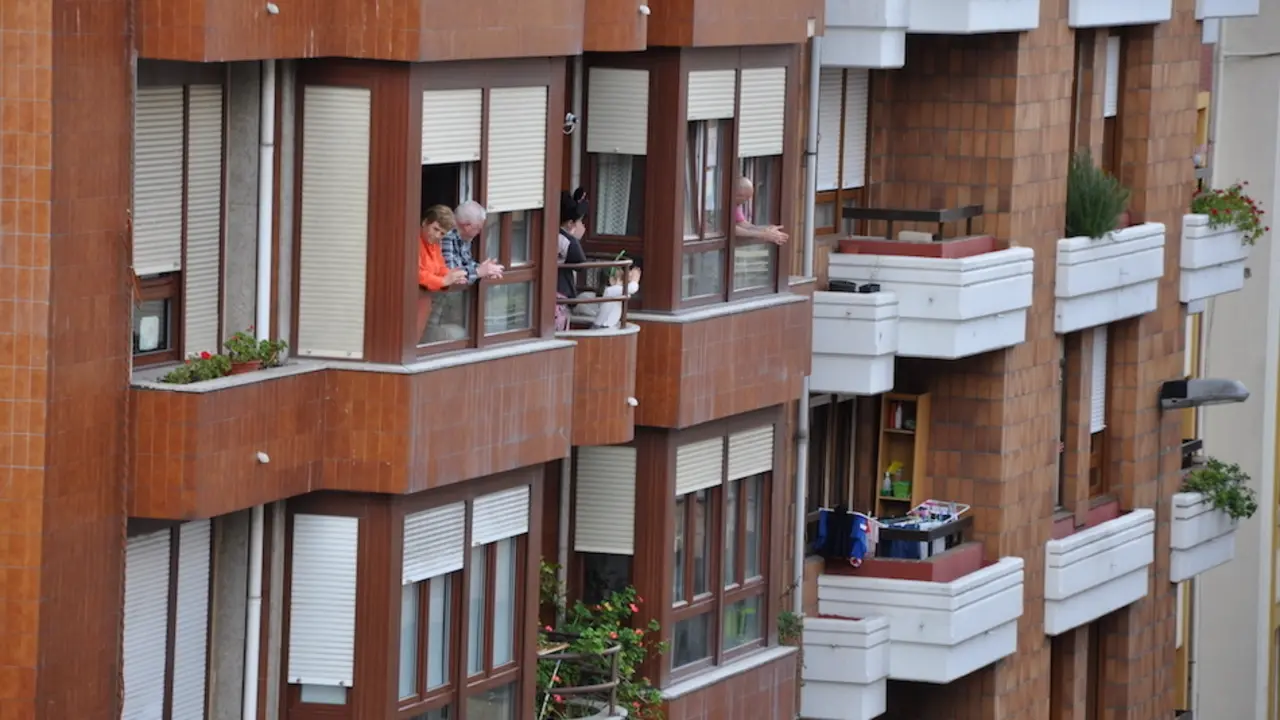 Varias personas en la ventana de sus casas en la calle Joaqu&iacute;n Cay&oacute;n de Torrelavega. / S.D.
