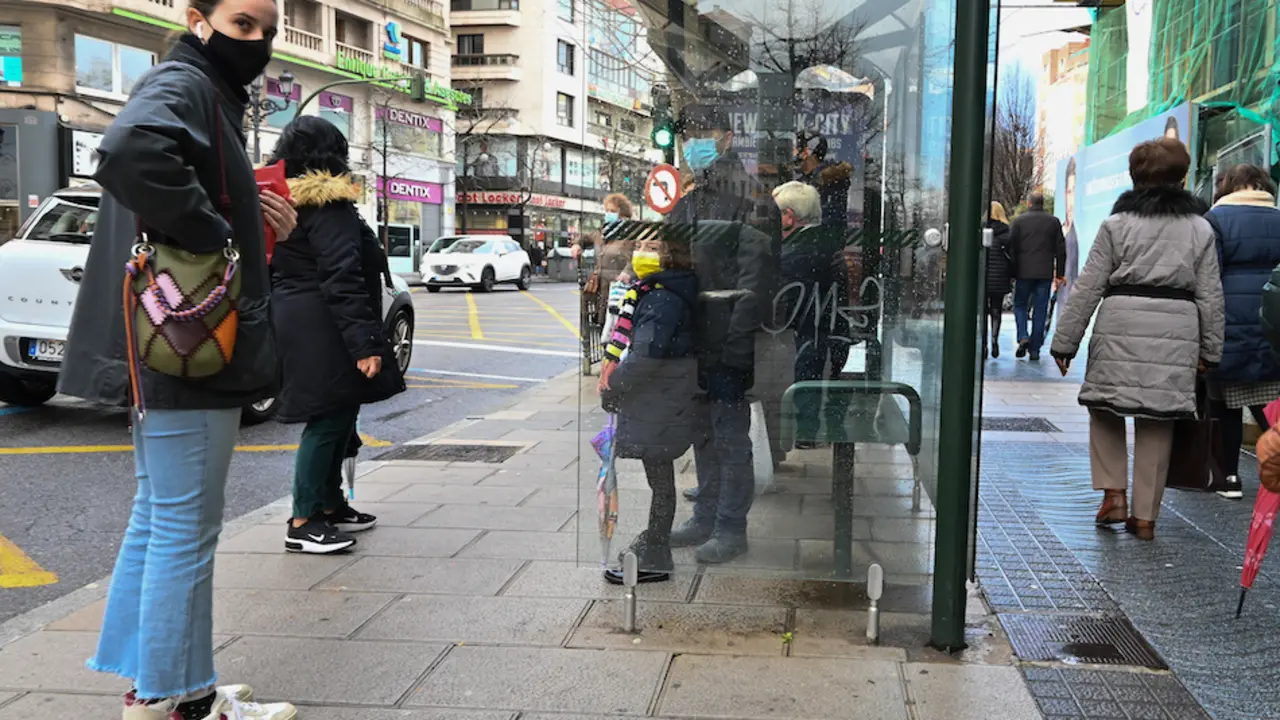 Varias personas con mascarilla en una parada de autob&uacute;s en el centro de Santander. / Hardy