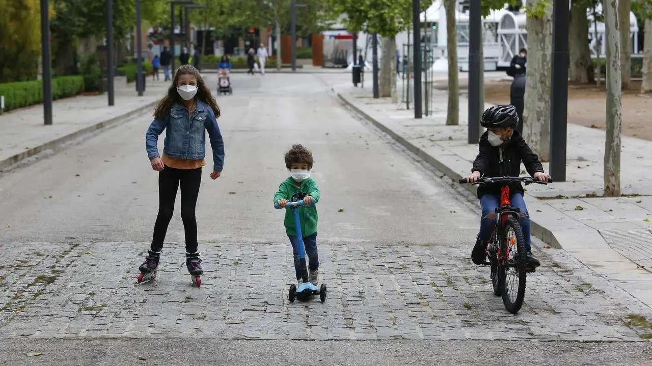 Tres ni&ntilde;os practican deporte al aire libre protegidos con mascarillas
