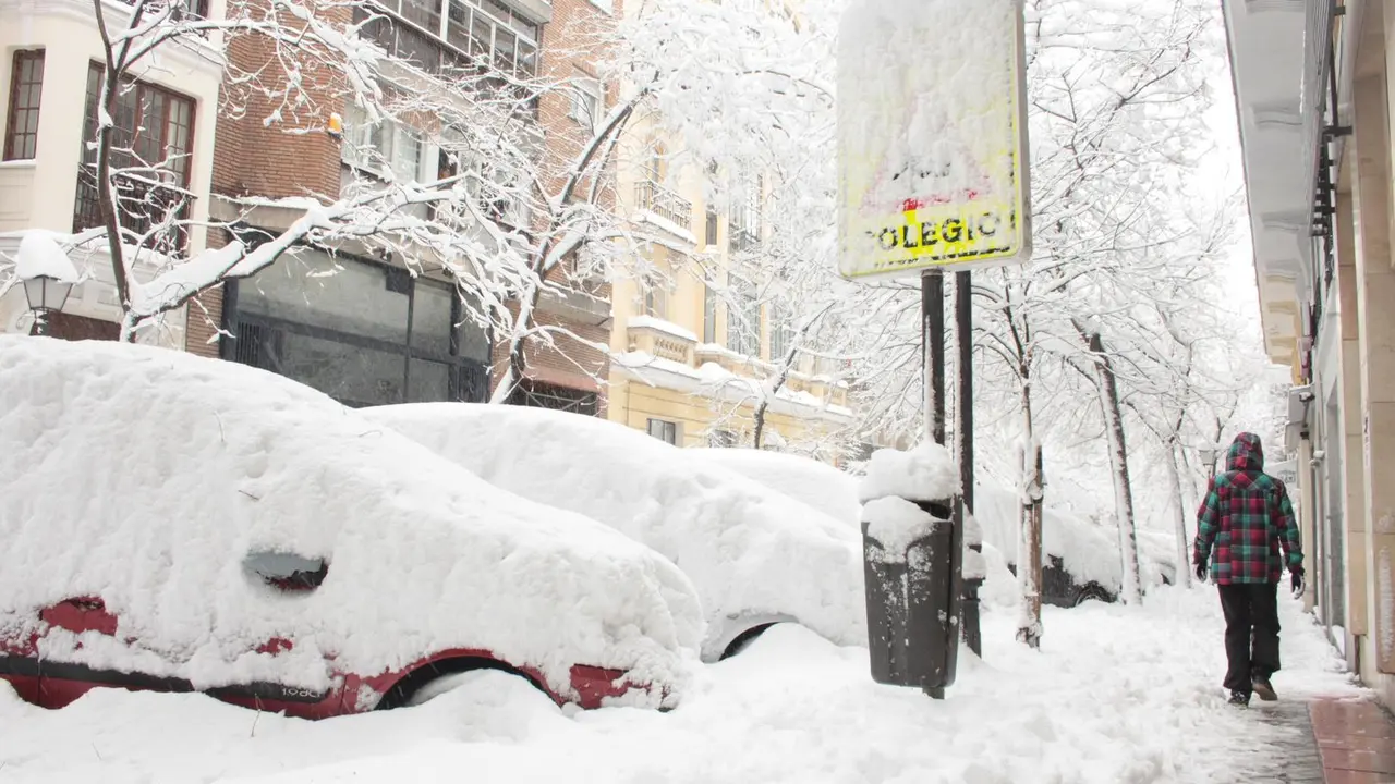 Una persona pasea por una c&eacute;ntrica calle cubierta de nieve junto al acceso de un colegio en Madrid (Espa&ntilde;a) a 9 de enero de 2021.
