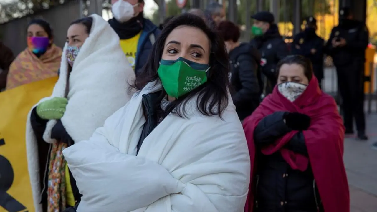 La portavoz de las Ampas de la Plataforma Escuela de Calor, Teresa Pablos (c), envuelta en un edred&oacute;n, durante la protesta convocada este mi&eacute;rcoles ante la sede de la Consejer&iacute;a de Educaci&oacute;n de la Junta de Andaluc&iacute;a en Sevilla para denunciar el fr&iacute;o que los ni&ntilde;os pasan en las aulas y exigir la puesta en marcha de la Ley de Bioclimatizaci&oacute;n. EFE/Julio Mu&ntilde;oz
