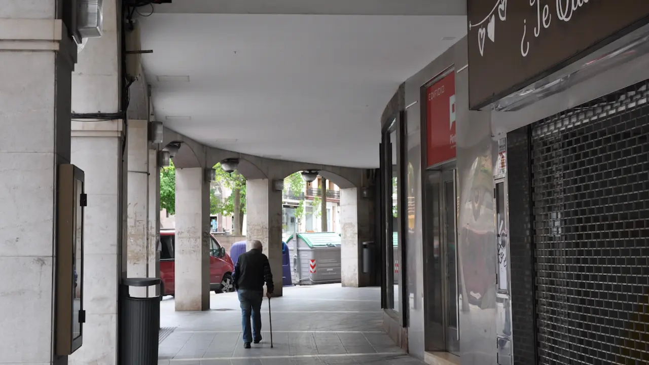 Una persona de avanzada edad pasea por los soportales en el centro de Torrelavega. / S.D.