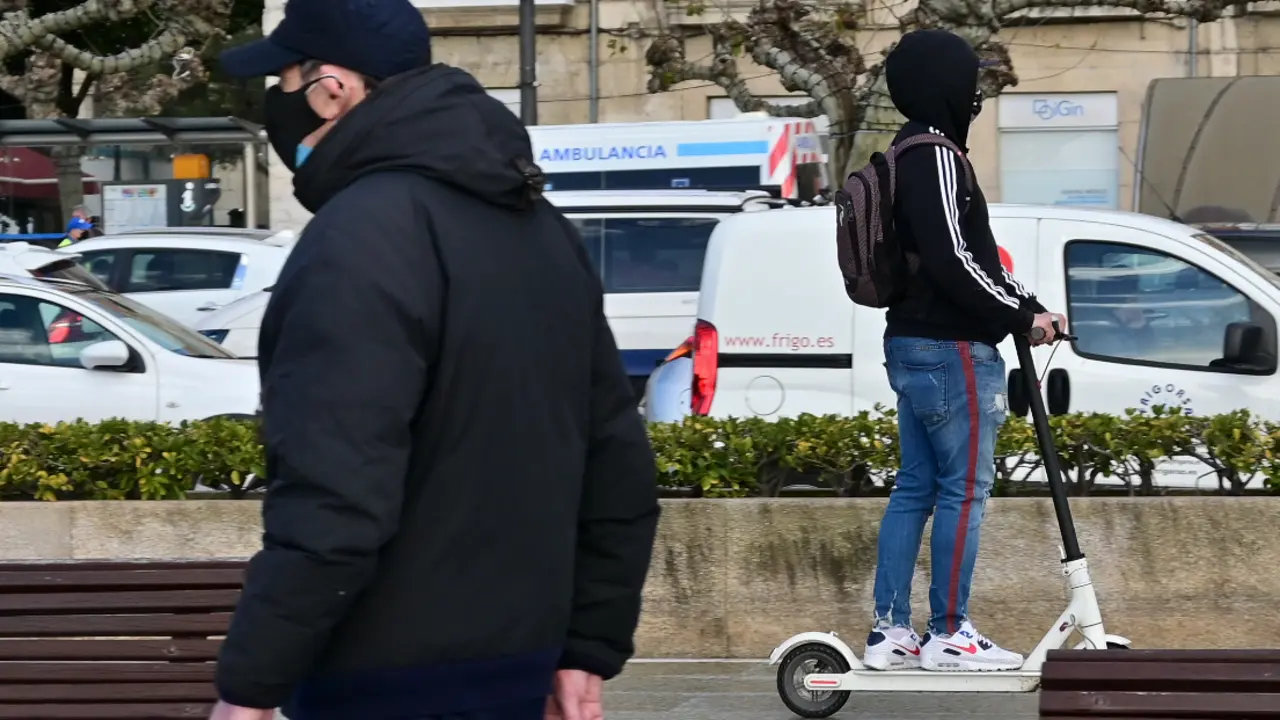 Dos personas con mascarilla por el paseo Pereda, mientras cruza a toda velocidad una ambulancia. / Hardy