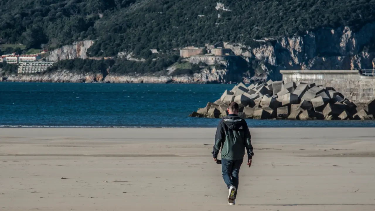 Un j&oacute;ven pasea por la playa de Laredo muicipio que quedar&aacute; confnado desde las 00.00 de ma&ntilde;ana. / Tono Reguera