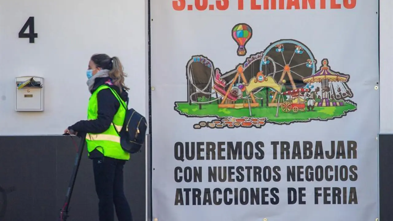 Una mujer pasa con un patinete el&eacute;ctrico por delante de un cartel que informa sobre la situaci&oacute;n de un sector empresarial afectado por la pandemia. EFE/ Cati Cladera