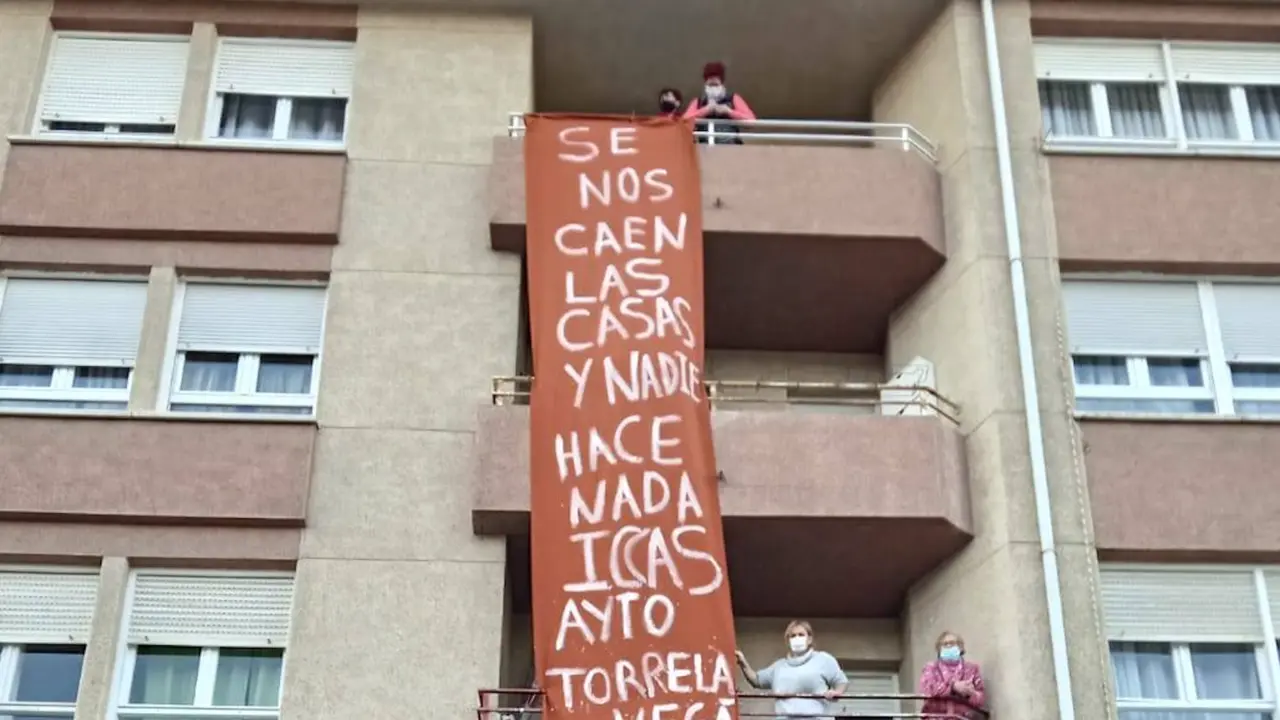 Vecinos junto a una pancarta en donde se puede leer "Se nos caen las casas y nadie hace nada, ICCAS, AYTO. TORRELAVEGA; S.O.S.".