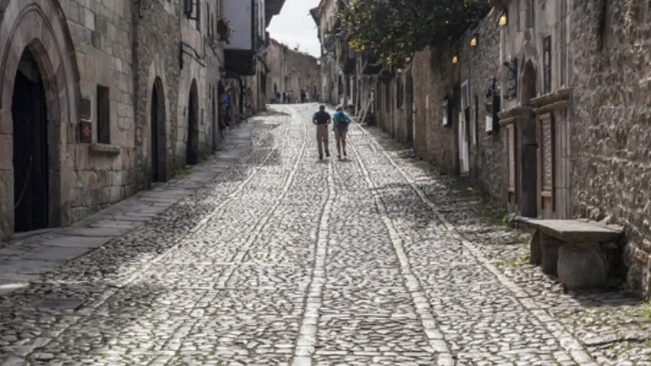 Dos turistas por la calle principal de Santillana del Mar. / ALERTA