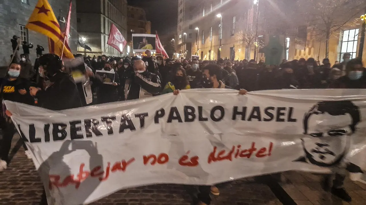 Varias personas sujetan una pancarta en la que se lee: `Libertat Pablo Hasel&acute; en una concentraci&oacute;n de m&aacute;s de 2.000 personas en rechazo al encarcelamiento de Pablo Hasel por las calles de Girona, Catalu&ntilde;a (Espa&ntilde;a), a 16 de febrero de 2021