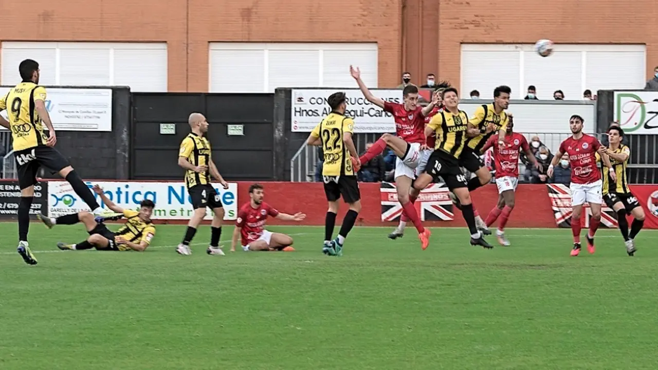 Un jugador del Laredo trata de rematar la pelota ante la oposici&oacute;n de los jugadores del Portugalete. / Reguera