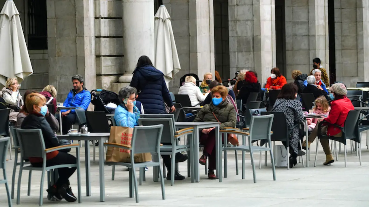 Varias personas con mascarilla disfrutan de la terraza de un establecimiento de hosteler&iacute;a en la plaza Porticada de Santander. / HARDY