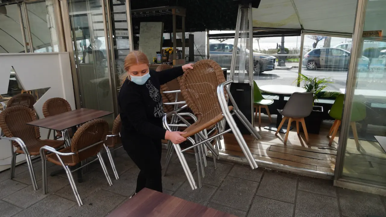 Una trabajadora de la hosteler&iacute;a prepara las sillas de su terraza en el Paseo Pereda de Santander. / HARDY