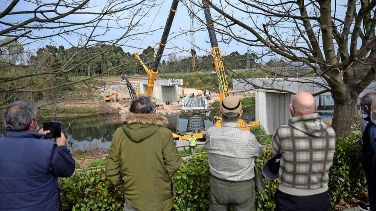 Varias personas observan los trabajos en la futura pasarela sobre el r&iacute;o Besaya en Torrelavega. / PEDRO PUENTE HOYOS