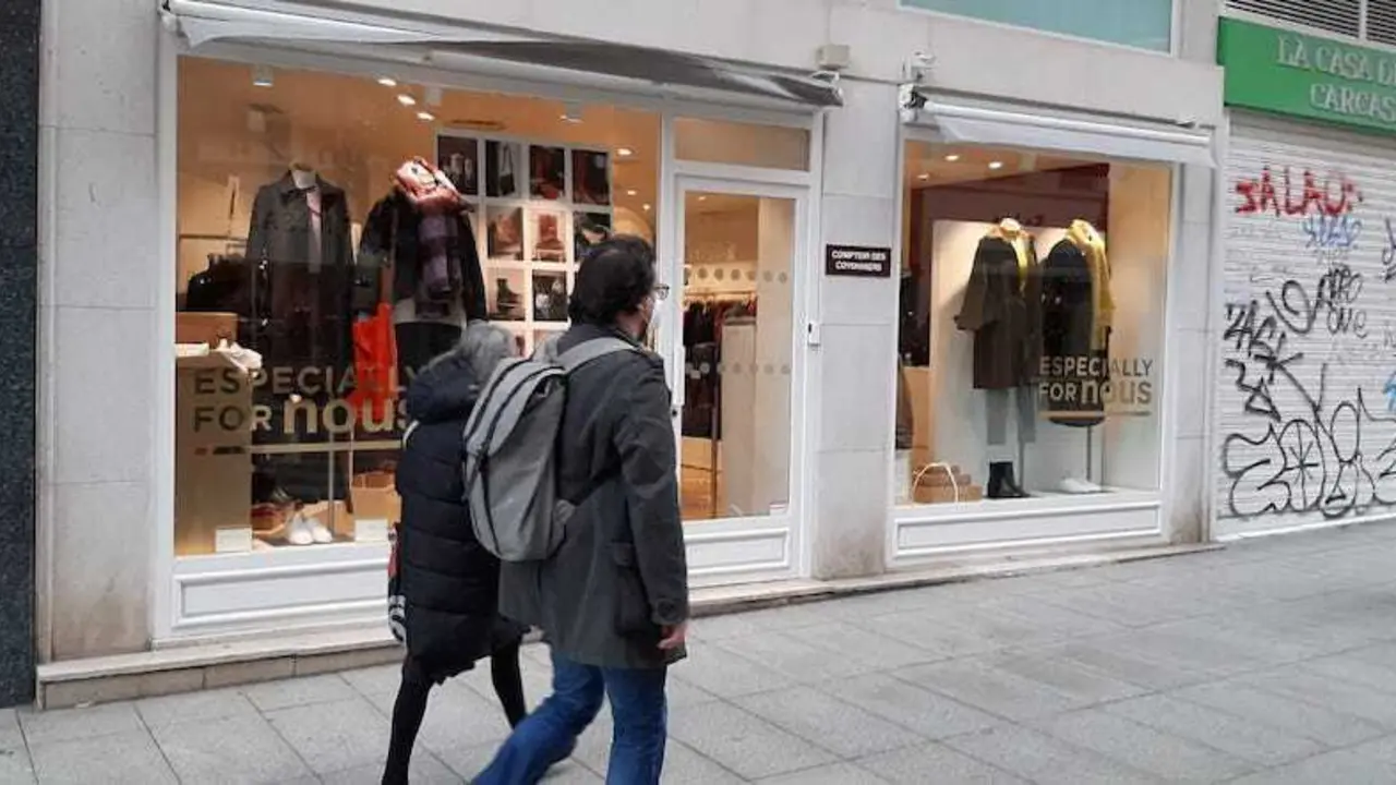 Dos personas caminan frente a un comercio en la calle Juan de Herrera de Santander. / S. DIAZ