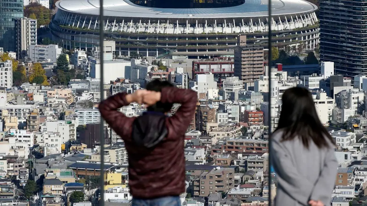 Dos personas obsesrvan el Estadio Nacional, la sede principal de los Juegos Ol&iacute;mpicos y Paral&iacute;mpicos en Tokio EFE/EPA/FRANCK ROBICHON
