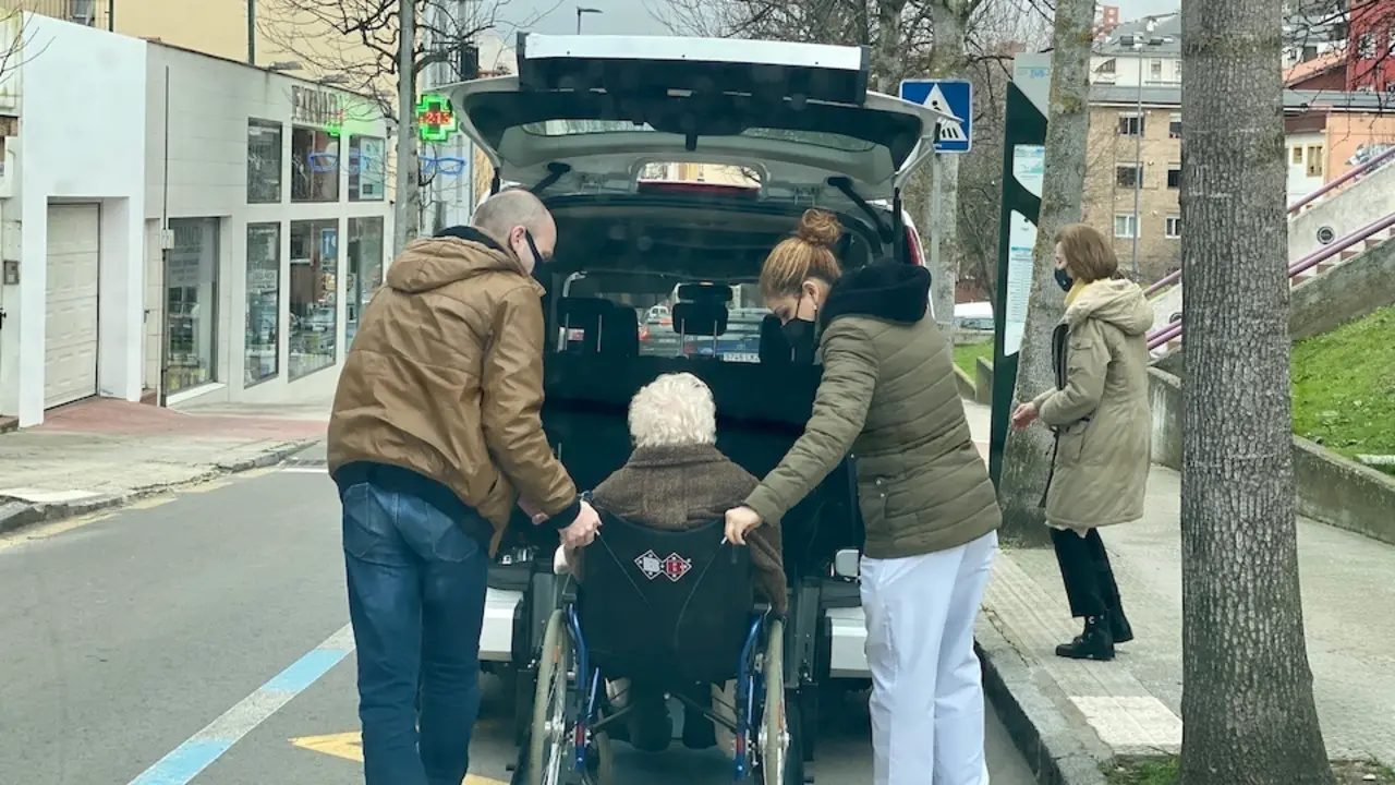 Dos personas personas ayudan a una mujer de avanzada edad a bajar del veh&iacute;culo en Santander. / Hardy