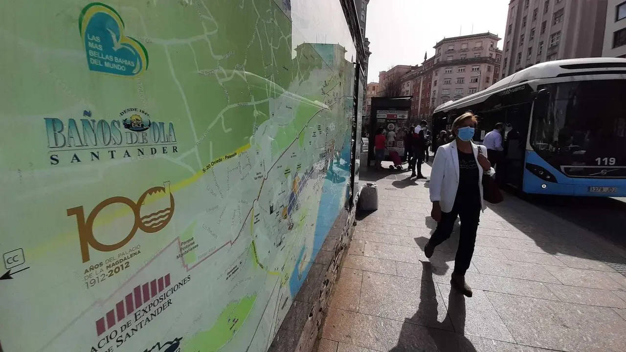 Una persona con mascarilla pasa delante de un cartel del Ayuntamiento donde se describe los puntos de inter&eacute;s tur&iacute;sticos. / S. D&iacute;az