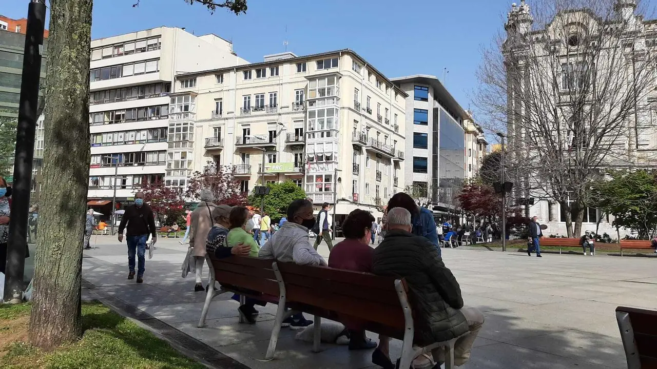 Varias personas sentadas en los bancos de la plaza del Ayuntamiento de Santander. / S. D&iacute;az