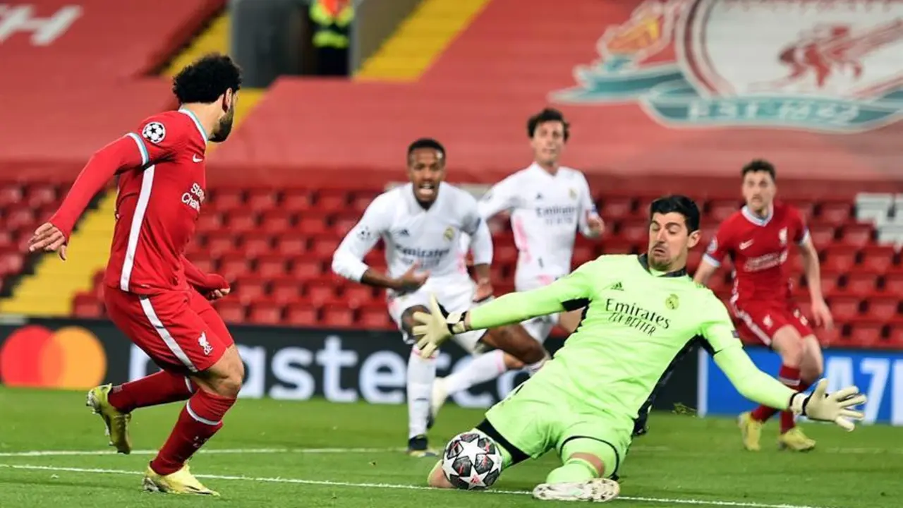 Liverpool's Mohamed Salah (L) en acci&oacute;n contra el portero del Real Madrid Thibaut Courtois (R) durante los cuartos de final de la Liga de Campeones de la UEFA, segundo partido de f&uacute;tbol entre el Liverpool FC y el Real Madrid en Liverpool, Reino Unido, 14 de abril de 2021. (Liga de Campeones, Reino Unido) EFE / EPA / Peter Powell