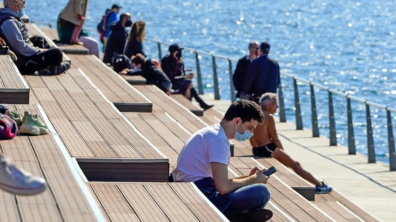 Un joven mira su m&oacute;vil mientras disfruta de un d&iacute;a primaveral ayer domingo en el dique de Gamazo, en Santander. / HARDY