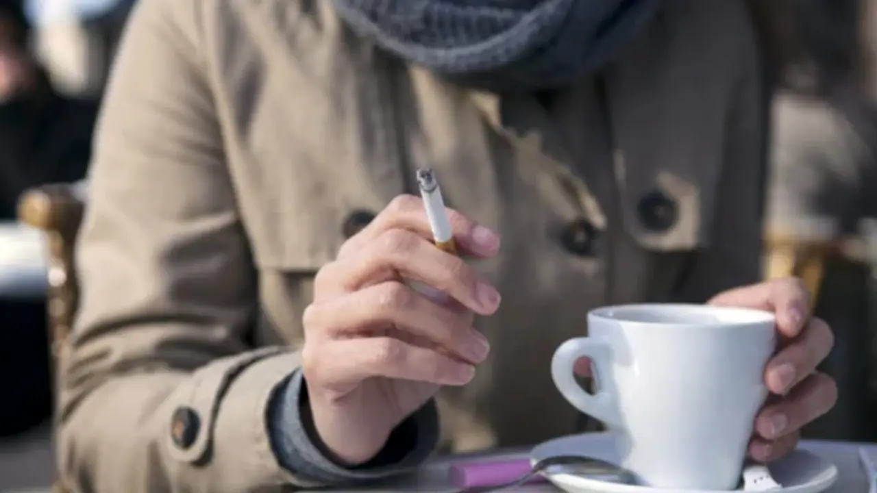 Una mujer fuma en una terraza de un bar.