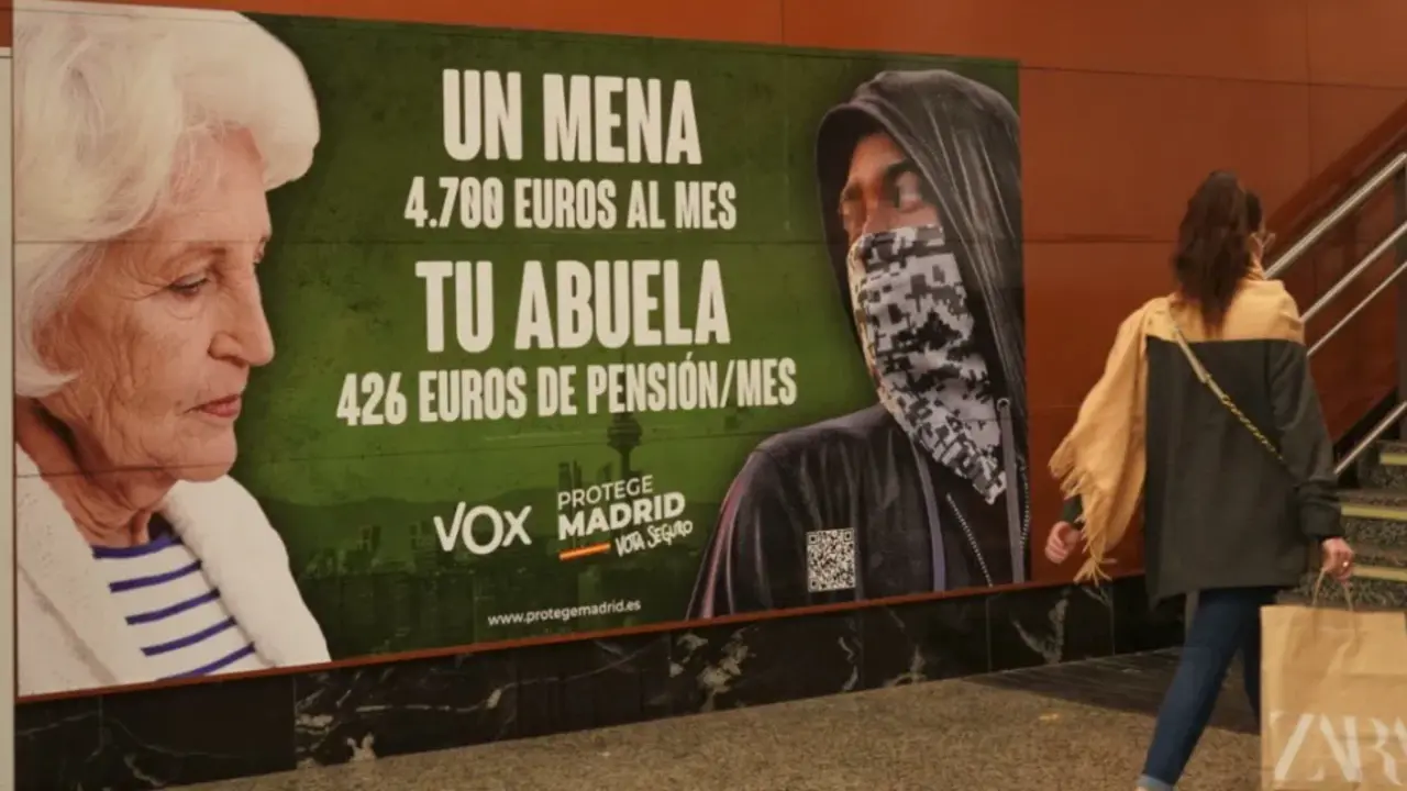 Una mujer pasa por delante del cartel electoral de Vox denunciado por posible delito de odio.