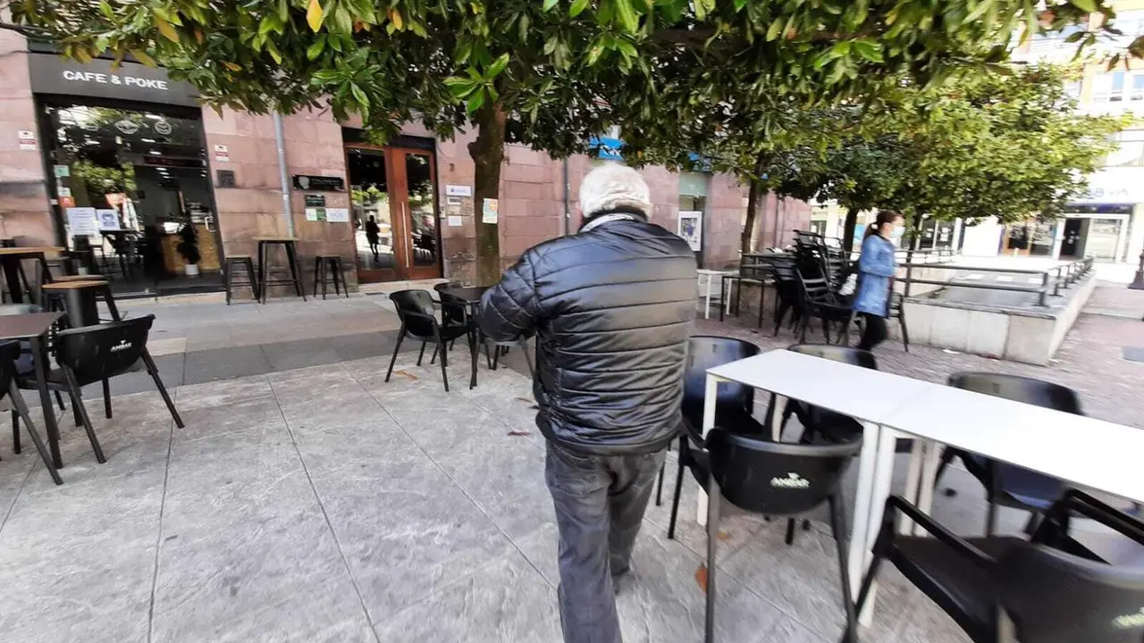 Una persona atraviesa una zona de terraza en la plaza Baldomero Iglesias de Torrelavega. / S. D&Iacute;AZ