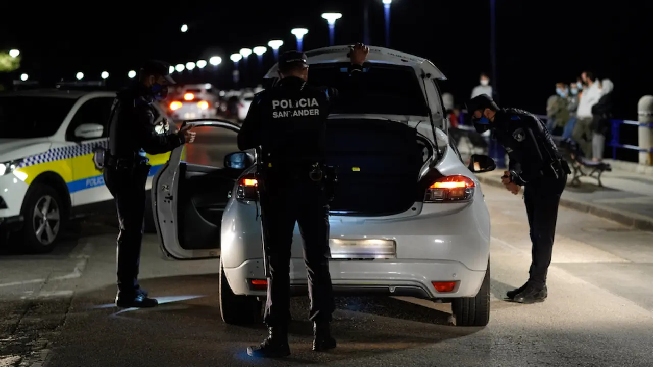 Varios polic&iacute;as revisan un coche durante el primero d&iacute;a sin el estado de alarma en el parking de la playa El Camello. / HARDY