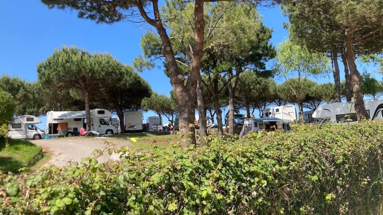 Autocaravanas estacionadas
este domingo en el Camping El
Rosal en San Vicente de la Barquera. Abajo un camarero prepara las mesas de la terraza de su
establecimiento para los futuros
comensales. / D&iacute;az