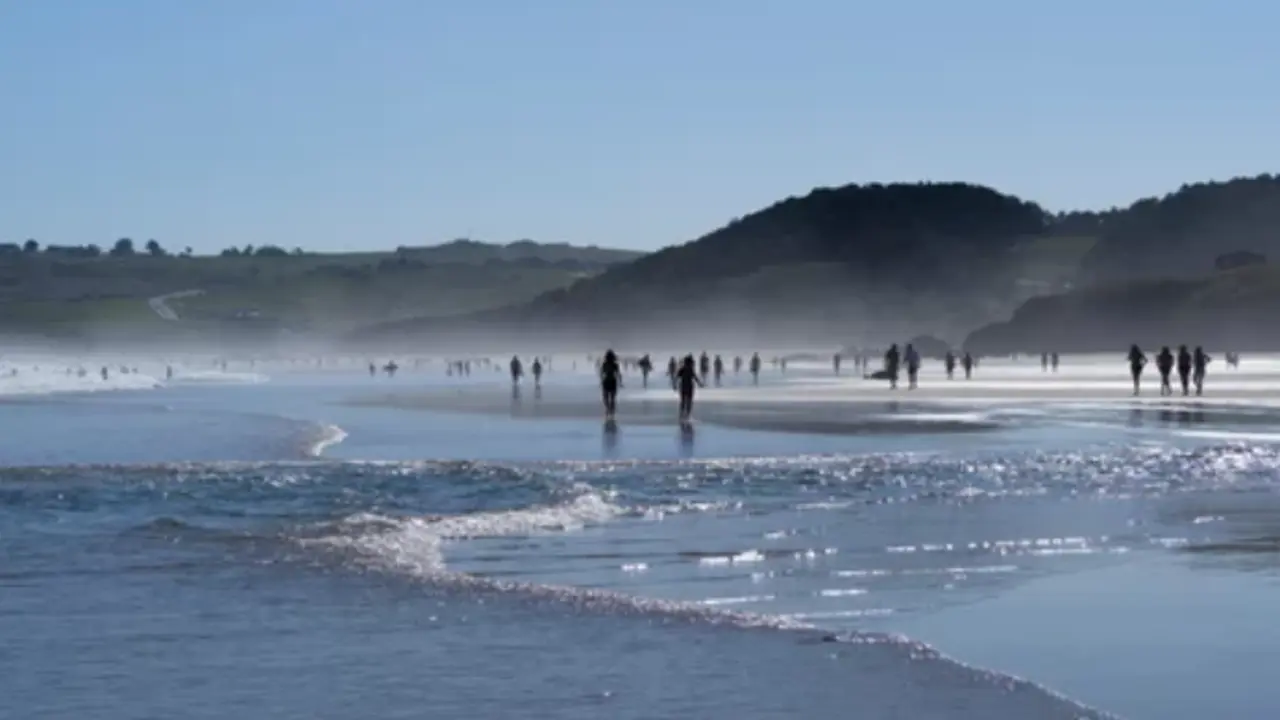 Varias personas caminan por una playa c&aacute;ntabra.