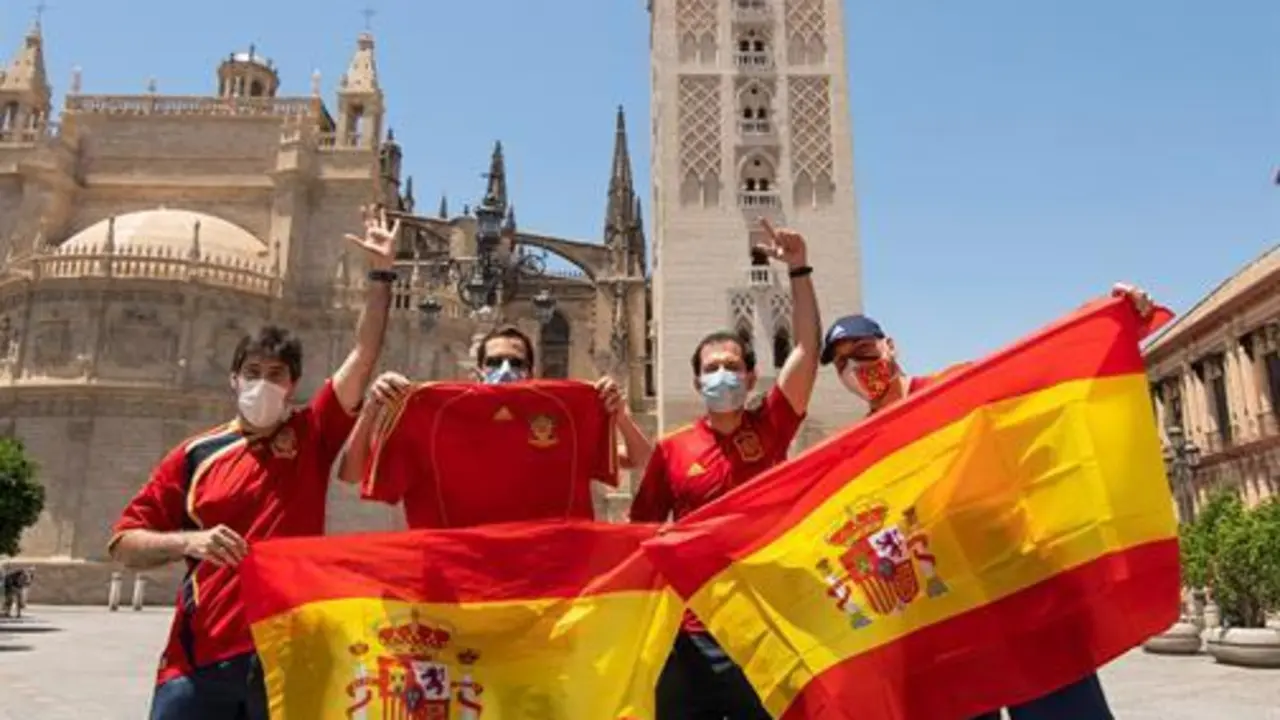 Aficionados de la selecci&oacute;n de Espa&ntilde;a delante de la Giralda y la Catedral en el centro de Sevilla antes del debut de Espa&ntilde;a frente a Suecia en esta Eurocopa 2020, que se jugar&aacute; hoy en el Estadio Ol&iacute;mpico de La Cartuja. EFE/ Ra&uacute;l Caro.