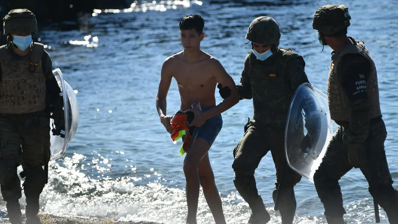 Dos militares del ej&eacute;rcito espa&ntilde;ol ayudan a un menor migrante procedente de Marruecos a su llegada a Ceuta