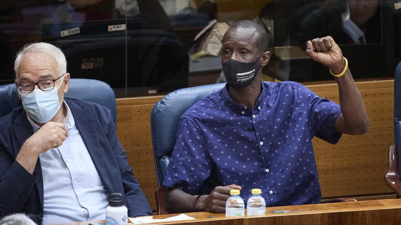 El portavoz del sindicato de manteros y miembro de la Asociaci&oacute;n de los Sin Papeles, Serigne Mbaye levanta el brazo para pedir la palabra por alusiones