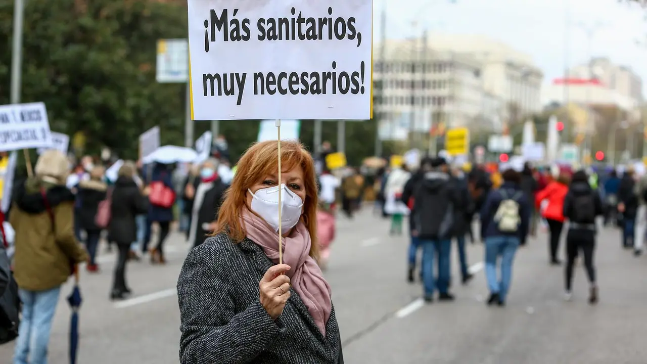 Archivo - Una mujer sostiene una pancarta donde se lee "&iexcl;M&aacute;s sanitarios, muy necesarios!" durante una manifestaci&oacute;n de la Marea Blanca en Madrid.