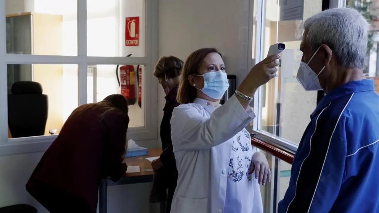 Una trabajadora toma la temperatura a un usuario a las puertas de un centro de mayores, este lunes, d&iacute;a de reapertura de estos centros en la Comunidad de Madrid. EFE/JP Gandul