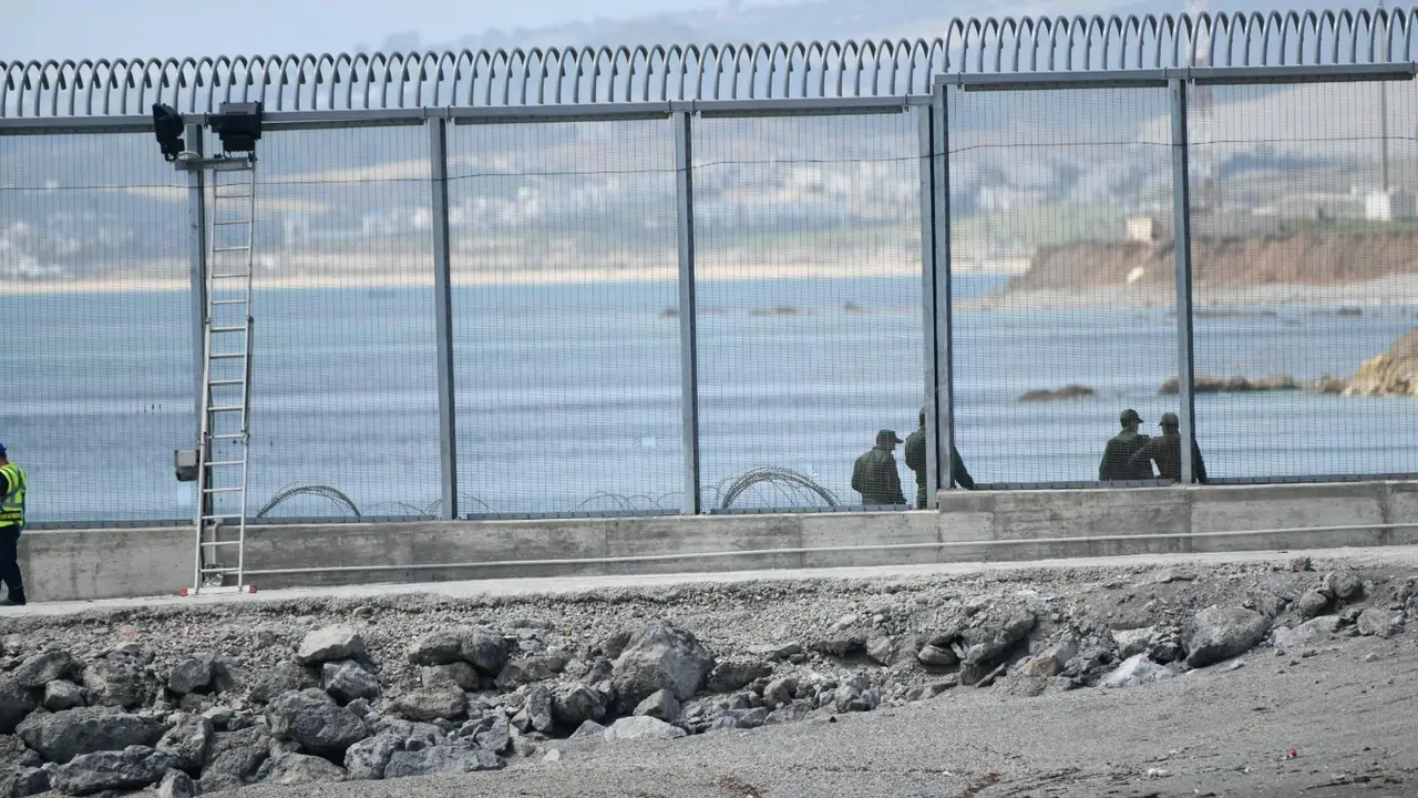 Agentes de la Gendarmer&iacute;a Real marroqu&iacute; y Fuerzas auxiliares (Mejania) levantan alambradas de concertinas en la parte inferior del vallado en el espig&oacute;n del Tarajal, a 1 de junio de 2021, en Marruecos.