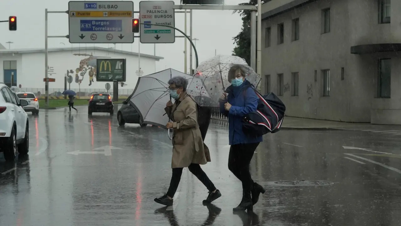 Dos personas cruzan una calle bajo la lluvia en Santander. / HARDY