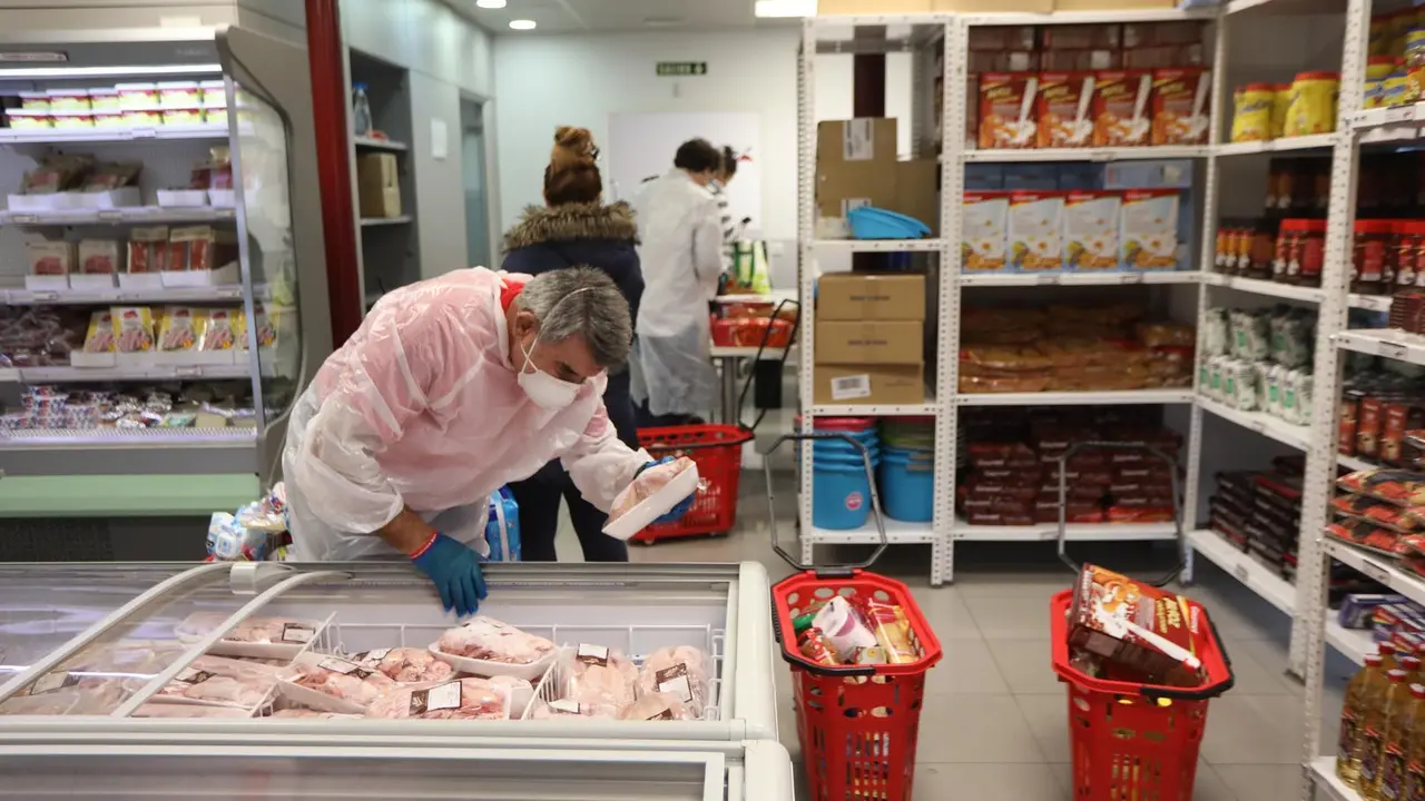 Archivo - Un voluntario manipula los alimentos de un refrigerador en el interior del economato solidario de C&aacute;ritas en Madrid.