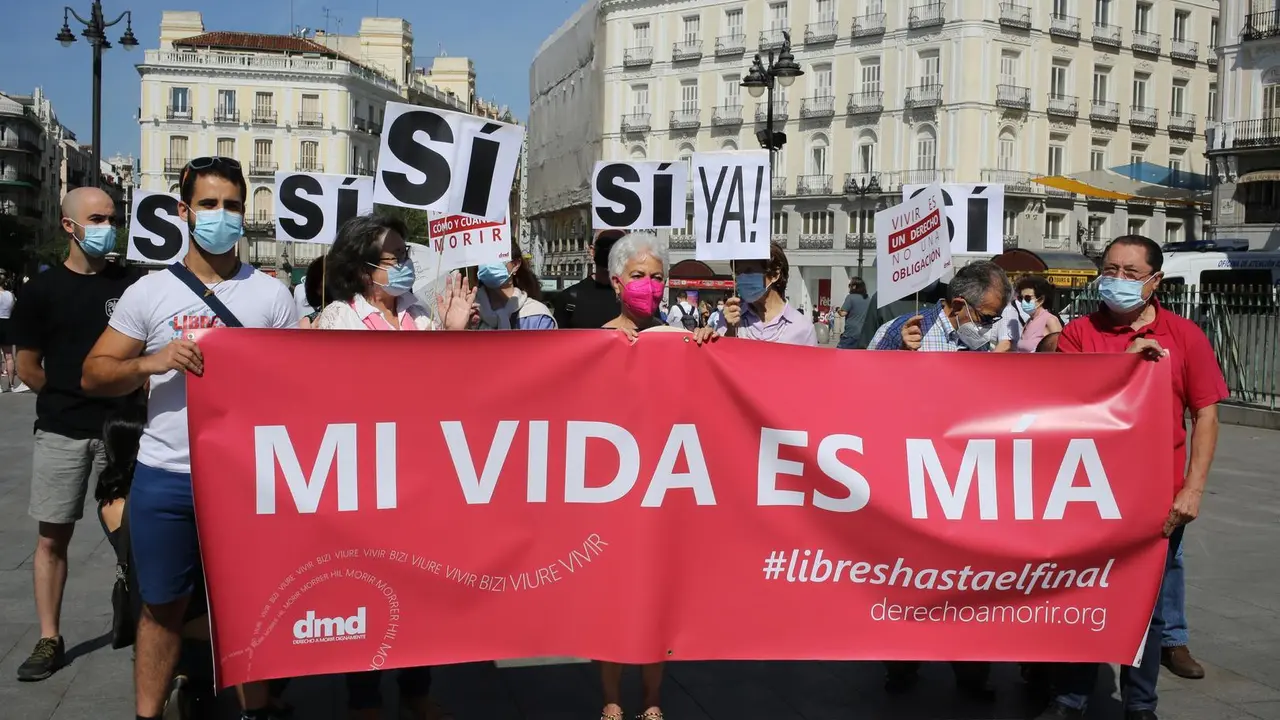 Un grupo de personas se re&uacute;ne sosteniendo pancartas y carteles durante la concentraci&oacute;n de la asociaci&oacute;n Derecho a Morir Dignamente (DMD) en la Puerta del Sol