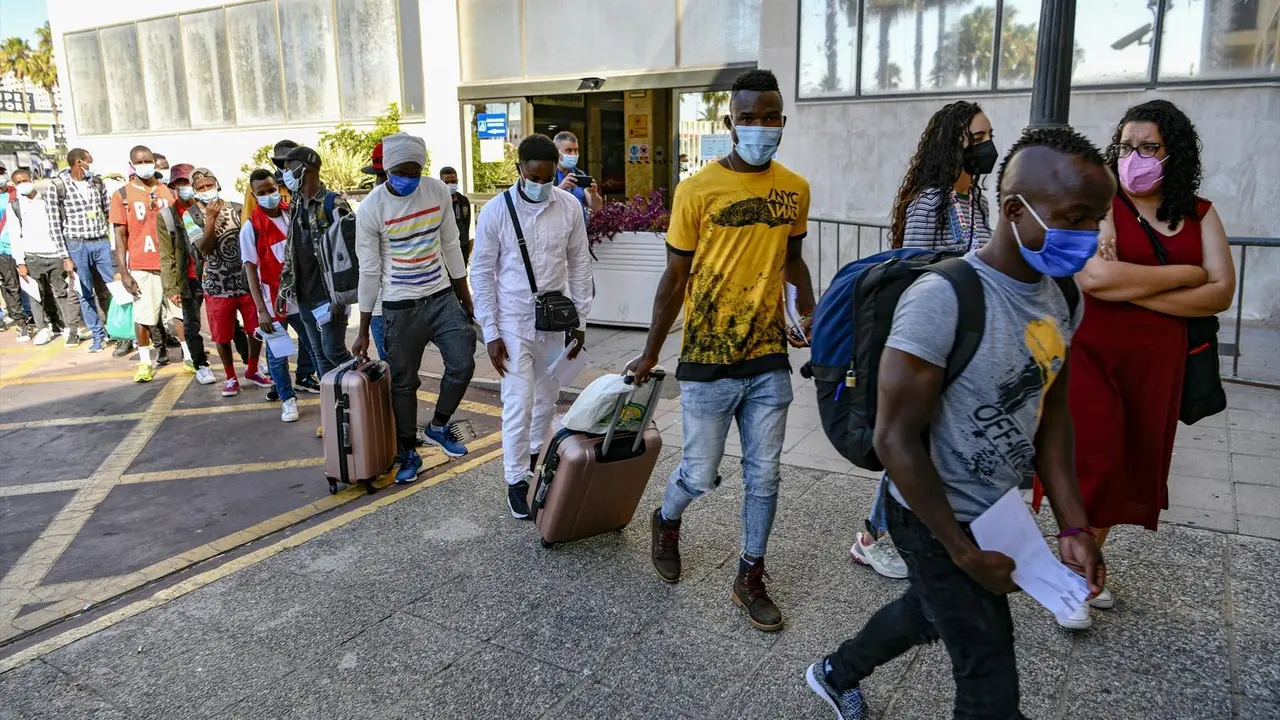 Varios inmigrantes subsaharianos hacen cola con maletas para viajar a la pen&iacute;nsula, donde ser&aacute;n acogidos por diferentes ONGs, en el CETI de Ceuta, a 23 de junio de 2021, en Ceuta (Espa&ntilde;a). Los 23 inmigrantes que viajan hoy a la pen&iacute;nsula, proceden en su m