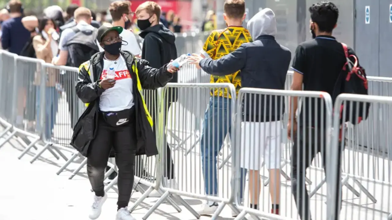 El personal reparte botellas de agua mientras la gente hace cola en un centro de vacunaci&oacute;n masiva contra el coronavirus en el estadio Emirates del Arsenal, en el norte de Londres. Fotograf&iacute;a: Dominic Lipinski/PA